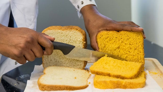 White bread, on left, and sweet potato bread being sliced with a knife