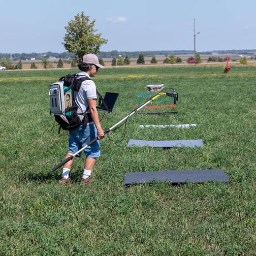 Research assistant Pedro Oliveira holding ASD Fiel Spec over colored squares in alfalfa field