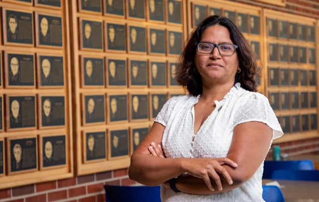 Assistant professor Anamika Prasad in front of wall of Distinguished Engineer plaques in CEH