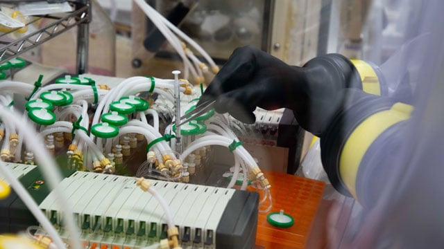 closeup of samples being take using a syringe from minibioreactors
