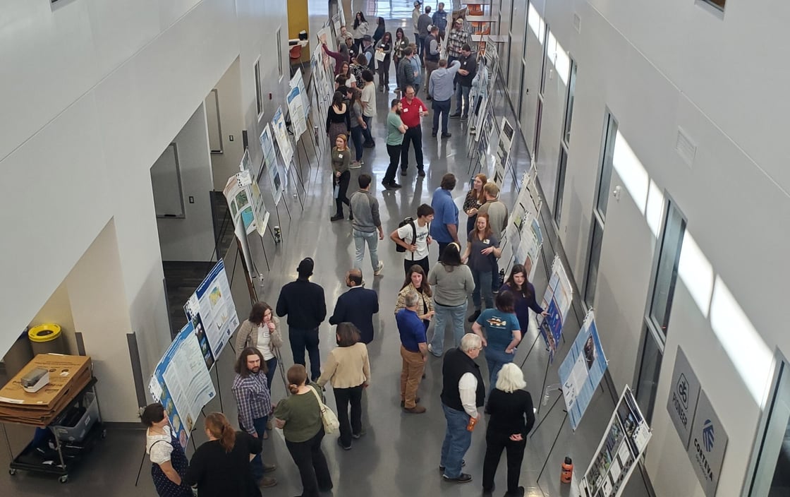 Graduate students presenting their research poster in Raven Atrium