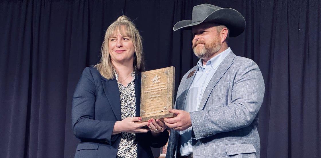 Krista Ehlert (left) holds her award plaque while standing with the SRM event host.