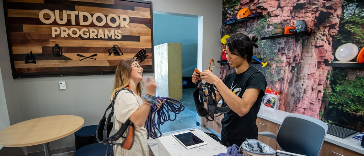 outdoor gear rental employee helping customer with ropes for rock climbing
