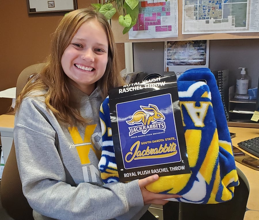 Izzy Tronnes is smiling holding the SDSU blanket.