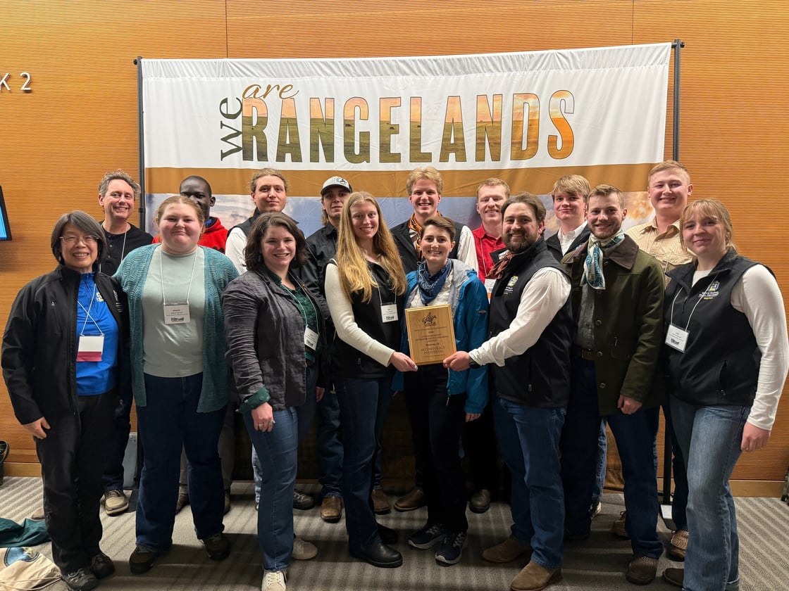 Range Team standing in front of a “We Are Rangelands” banner, with two people in the center holding an award plaque.
