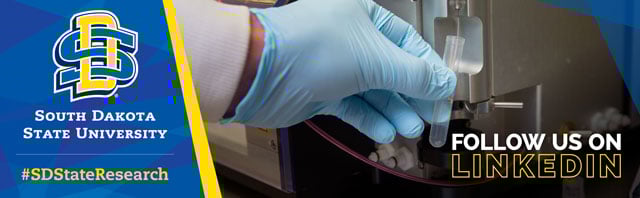 gloved hand with sample in vial