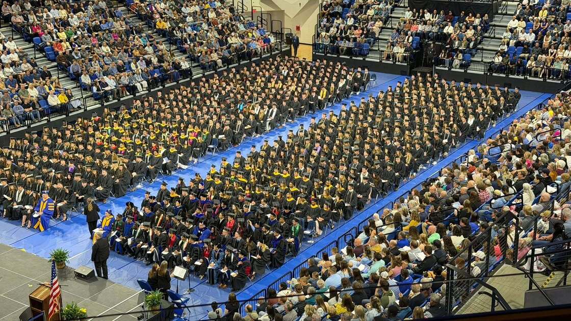 Packed SDSU graduation ceremony inside a crowded arena with graduates and guests.
