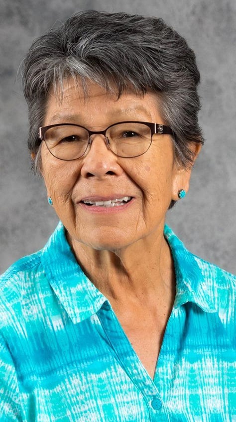 bev warne smiling in a portrait photo wearing a turquoise shirt and earrings