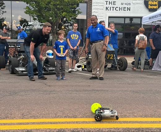 dean Kumar with a young child driving a robot 