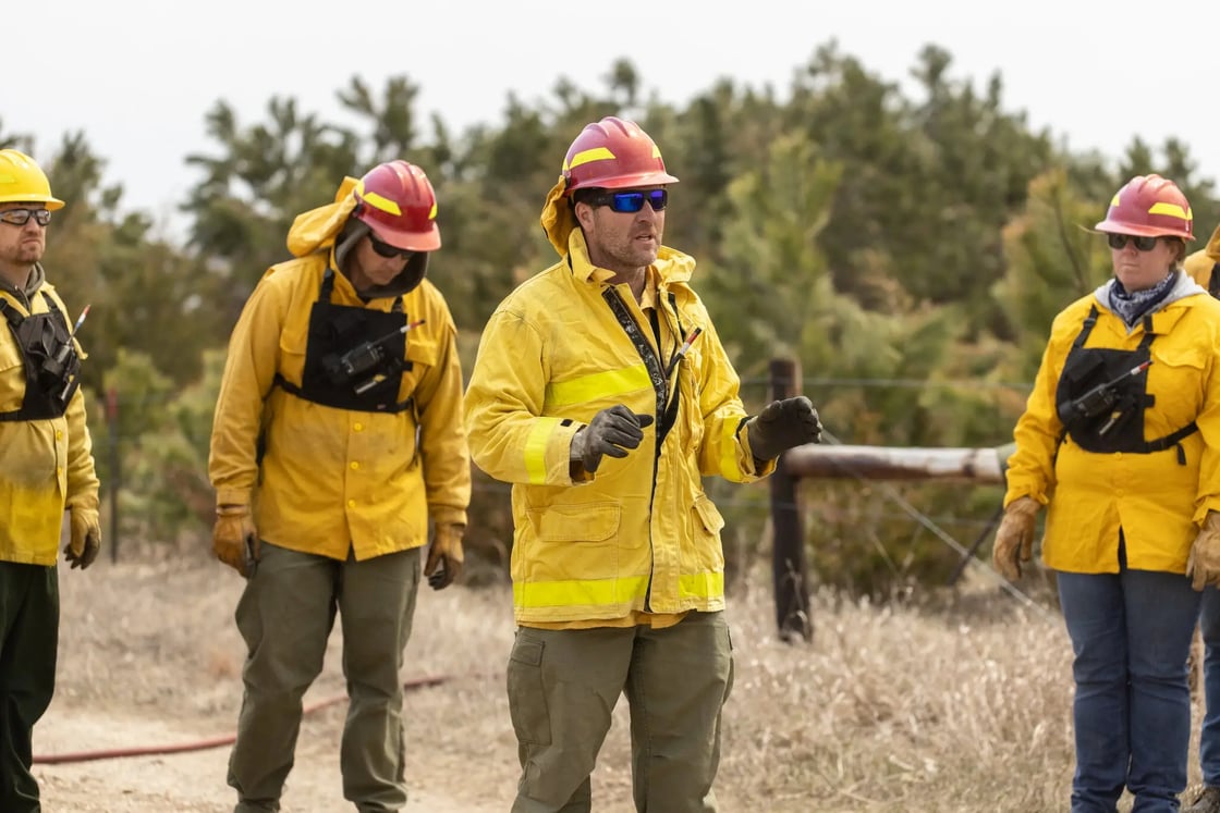 Pete Bauman in the center is giving a training session as wearing the yellow jacket and red hard shell helmet.