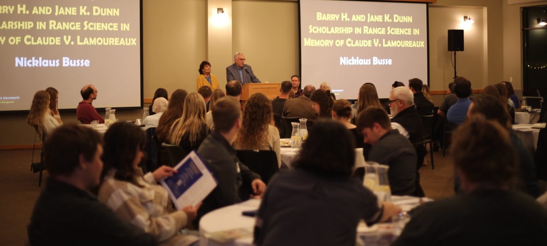 Reception hall overview. Participants are sitting and looking at President Barry Dunn on the podium in front along with Jane Dunn.
