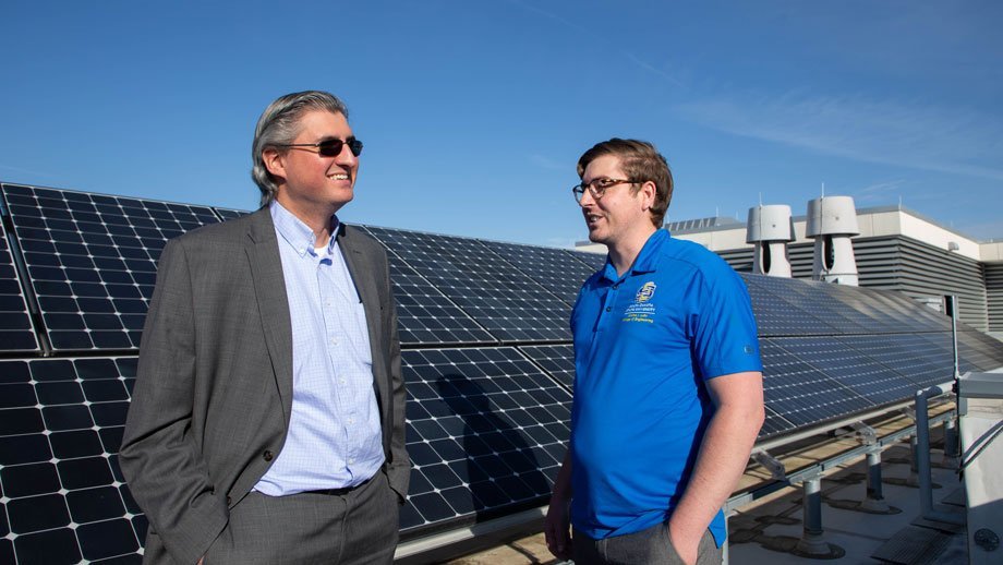 Reinaldo Tonkoski, left, and Tim Hansen standing in front of solar panels atop Daktronics Hall
