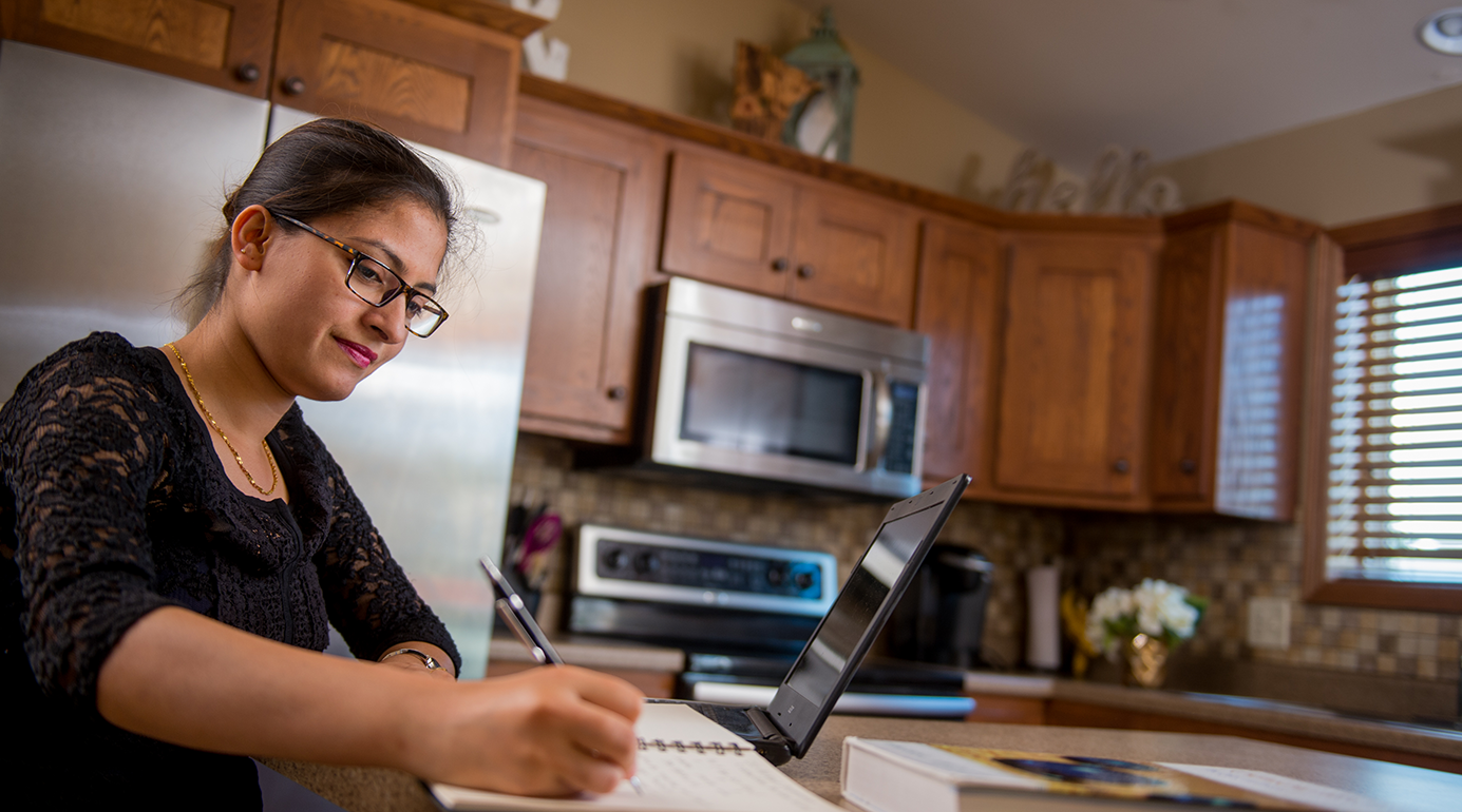 female student completing online classes in her kitchen